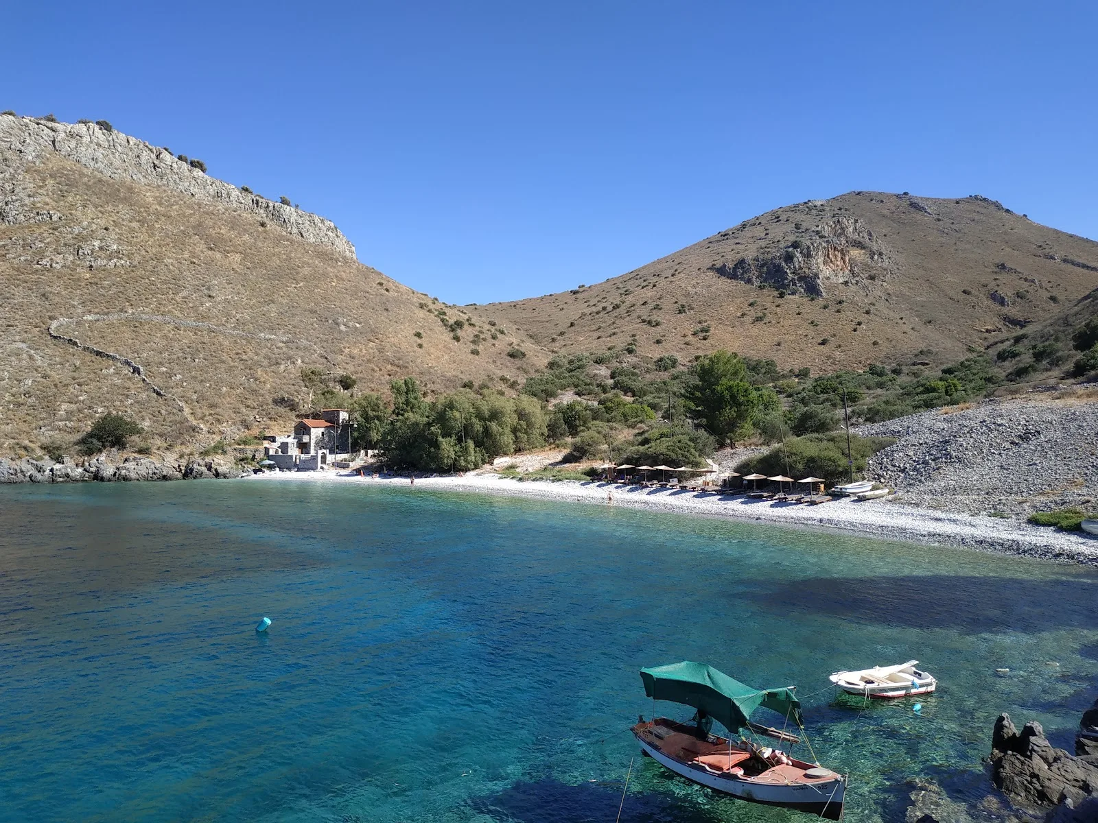 Άγριος όρμος με βότσαλα και βαθιά γαλάζια νερά στην παραλία Άμπελος στη Μάνη