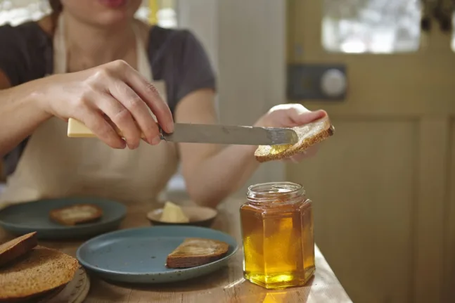 Φέτα ψωμιού ολικής αλέσεως με μέλι σε πιάτο για θέμα σχετικά με το σάκχαρο στο αίμα