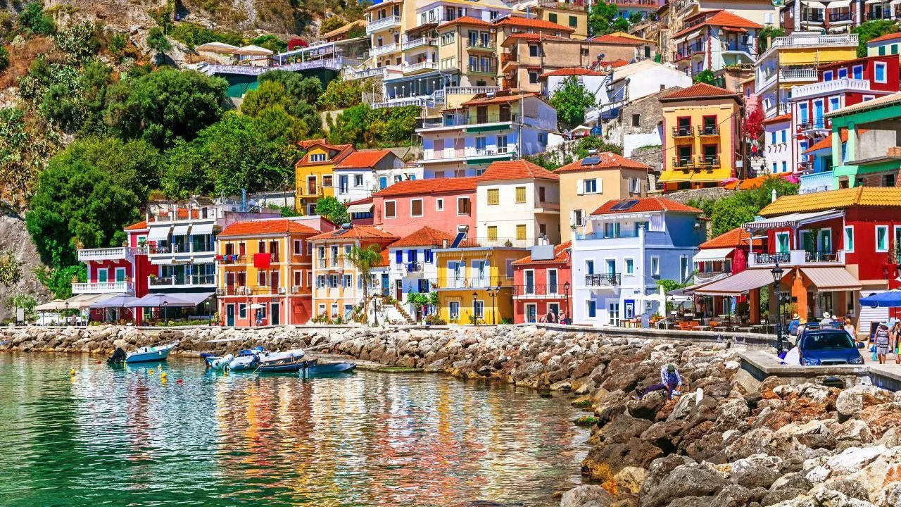 Πάργα: Παραλίες, κάστρο, Παξοί και Αντίπαξοι σε μία απόδραση που τα έχει όλα Πολύχρωμα σπίτια στην Πάργα χτισμένα πάνω από το παραθαλάσσιο μέτωπο, με μικρές βάρκες και αντανακλάσεις στα ήρεμα νερά
