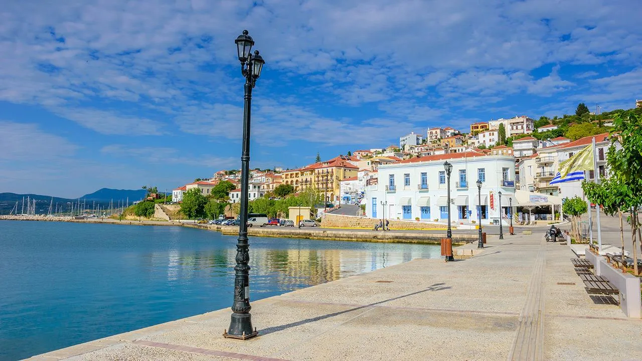 Το καλοκαίρι έχει σχήμα Ω – Ο ολοκληρωμένος καλοκαιρινός οδηγός για τη δυτική Μεσσηνία Η παραλιακή οδός της Πύλου με θέα στα νερά του λιμανιού και τα σπίτια της πόλης