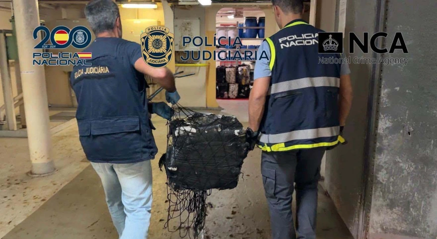Αστυνομικοί μεταφέρουν ένα από τα δεμένα φορτία που κατασχέθηκαν κατά την έρευνα στο εμπορικό πλοίο