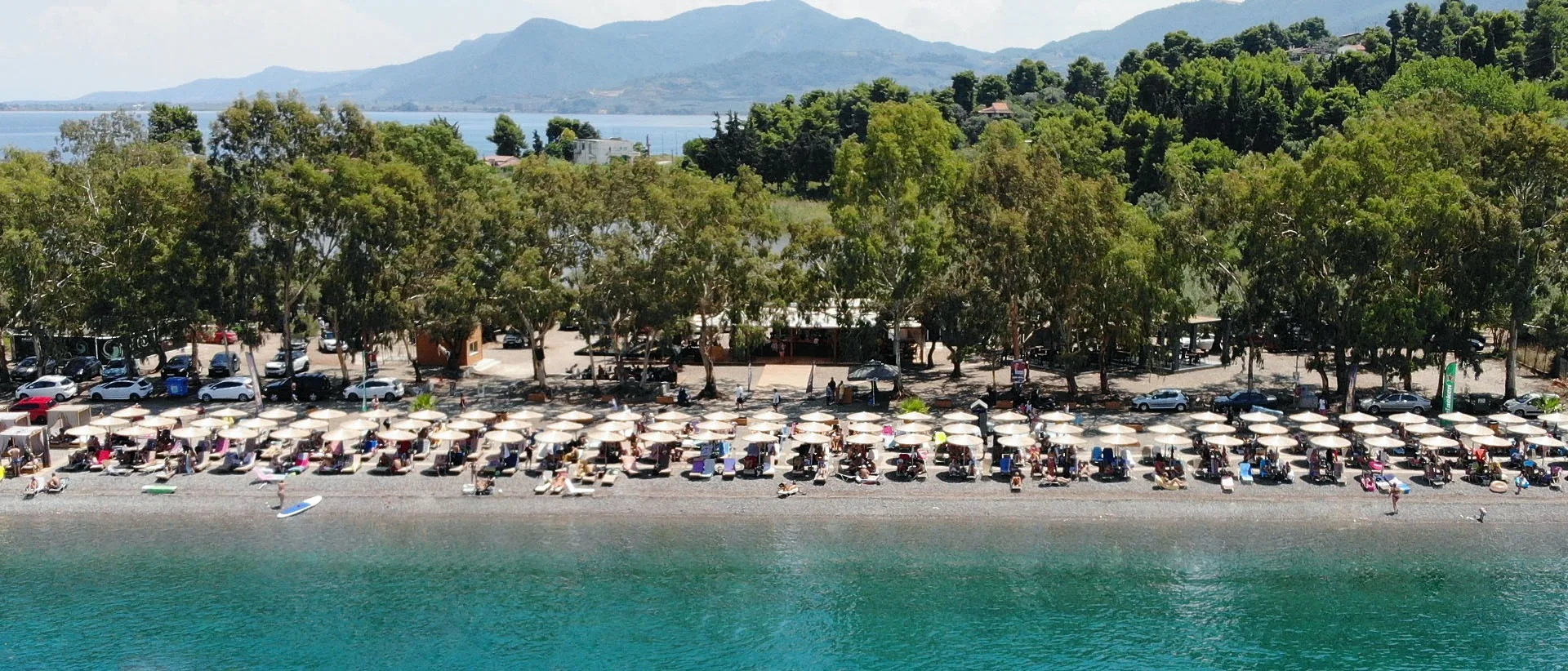 Δεν έκλεισες ακόμα διακοπές; 5 μέρη δίπλα στη θάλασσα όπου αξίζει να ψάξεις δωμάτιο τώρα Η παραλία Ασπρονέρι κοντά στα Καμένα Βούρλα με ξαπλώστρες, ομπρέλες και καταπράσινο ορεινό τοπίο