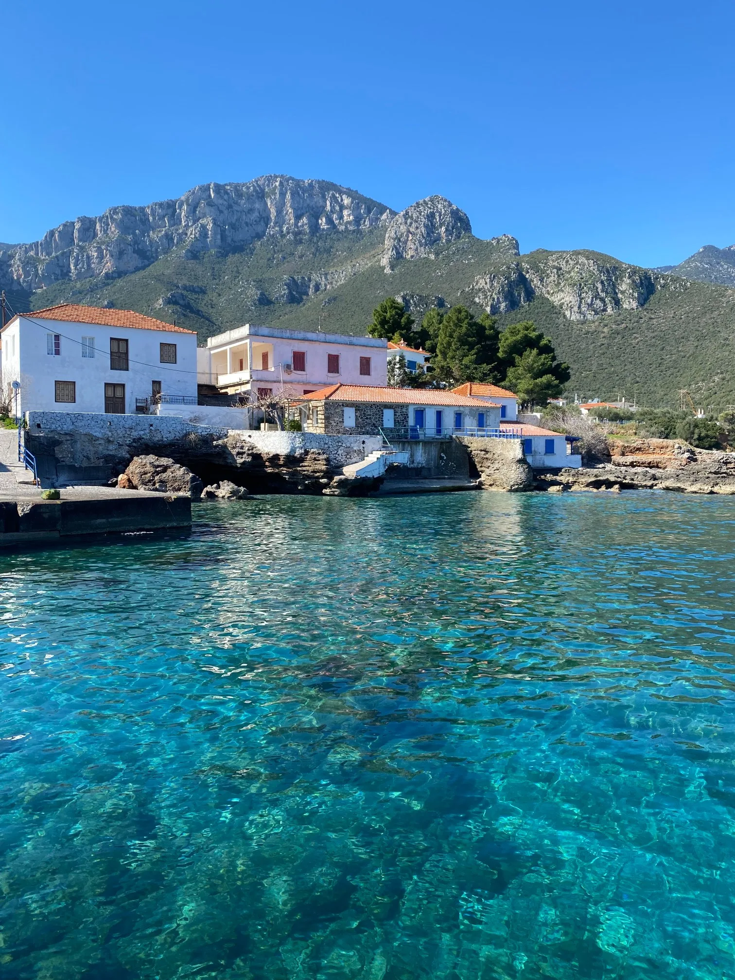 Χωρίς πλοίο, μακριά από τα συνηθισμένα: 6 στάσεις από το Λεωνίδιο στη Μονεμβασιά Πέτρινα και λευκά σπίτια στην ακτή του Κυπαρισσιού, με διάφανα γαλαζοπράσινα νερά και τα βουνά του Πάρνωνα στο βάθος