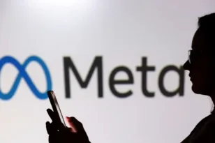 Σκιά ανθρώπου που χρησιμοποιεί smartphone μπροστά από το λογότυπο της Meta