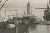 Ασπρόμαυρη φωτογραφία του λιμανιού της Πάτρας το 1910, με πλοία και τον παλιό φάρο.