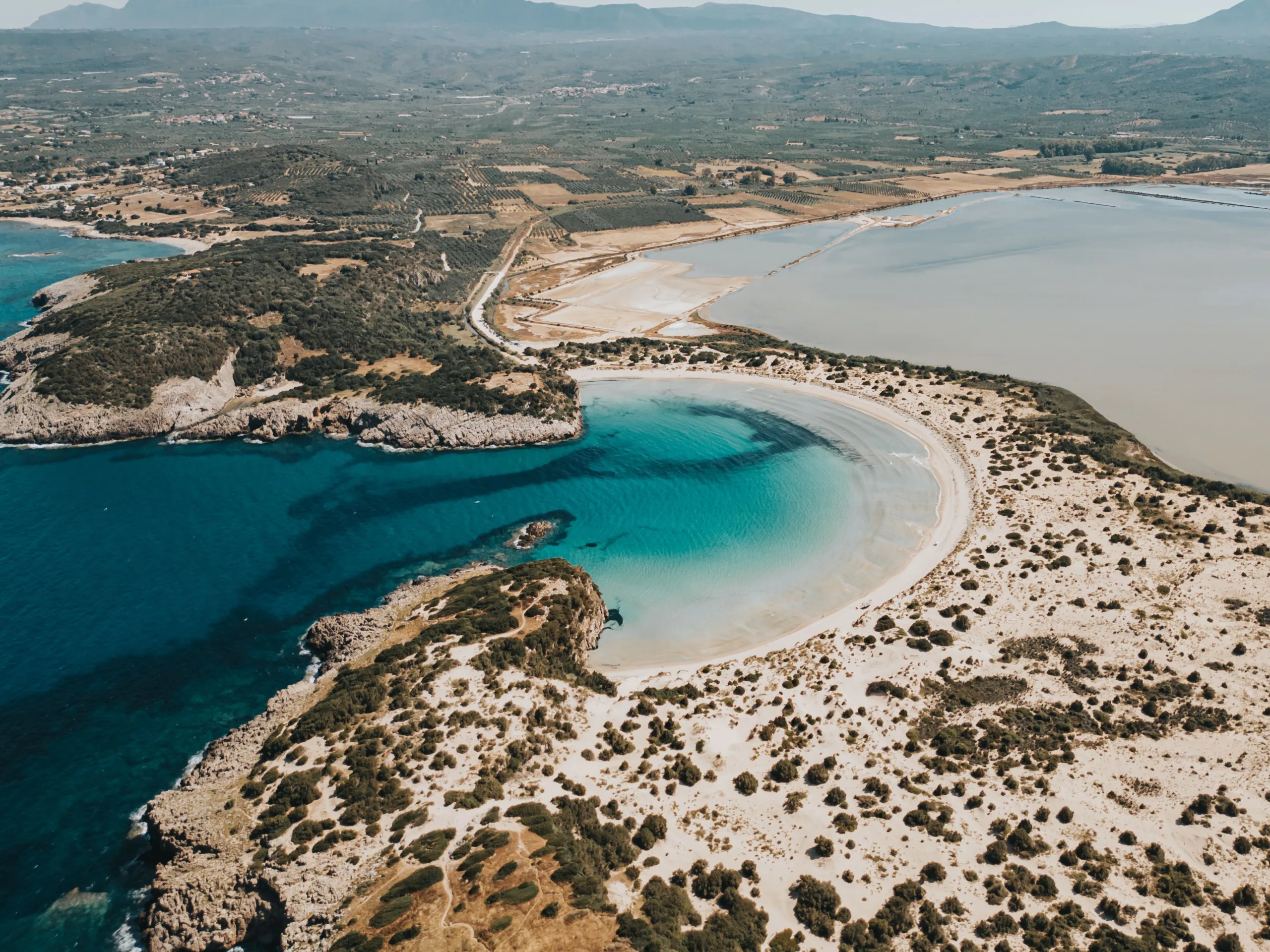 Η διαδρομή της Πελοποννήσου που μοιάζει φτιαγμένη για τον Αύγουστο Πανοραμική άποψη της Βοϊδοκοιλιάς με την αμμουδιά σε σχήμα Ω και τη λιμνοθάλασσα της Γιάλοβας