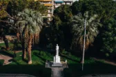 Το Άγαλμα της Δόξας στην πλατεία Όλγας της Πάτρας, ανάμεσα σε δέντρα και φοίνικες